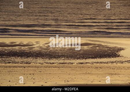 Ruisseau des modèles complexes de sable à marée basse par une mer calme dans la lumière dorée de l'aube, Aberdeen, Écosse, Royaume-Uni. Banque D'Images