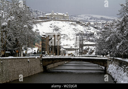 28 mars 1993 pendant le siège de Sarajevo : 28 mars 1993 La vue vers l'est le long de la rivière Miljacka depuis l'extrémité sud de l'Principov Bridge (connu comme le pont Latin) à l'Zerajica aujourd'hui appelé le pont (pont de l'Empereur). L'holocauste de National Art Gallery et de la Bibliothèque se tient sur la gauche et au-dessus c'est la caserne militaire de Jajce. Banque D'Images