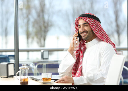 Happy arab man talking on smart phone assis dans un café Banque D'Images