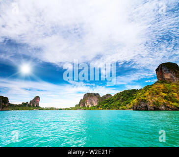 De grands rochers sur la rive avec des arbres et arbustes. effacer l'eau de mer et de ciel bleu avec des nuages blancs. L'arrière-plan parfait Banque D'Images