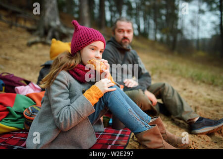 Jolie petite soeurs et leur père having picnic par un feu par une froide journée d'automne. Les enfants s'amuser au feu de camp. Camping avec les enfants dans la forêt d'automne Banque D'Images