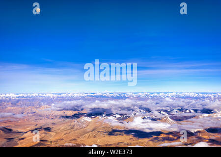 Pleine lune sur les montagnes arides de l'intérieur de la gamme du Zanskar Himalaya, l'Inde. Prises d'un avion sur un début de juillet matin. L'orientation paysage. Banque D'Images