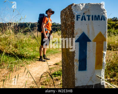 Le Portugal. 31 mai, 2019. Un pèlerin est à côté d'une pierre avec un jaune et une flèche bleue indiquant la façon de Fatima.Le Camino de Santiago (Chemin de Saint Jacques) est un vaste réseau de routes de pèlerinage antique s'étendant à travers l'Europe et de venir ensemble à la tombe de saint Jacques (Santiago en espagnol) à Santiago de Compostelle, dans le nord-ouest de l'Espagne. Chaque année, des milliers de personnes de diverses origines à pied le Chemin de Compostelle seuls ou en groupes organisés. Credit : Ana Fernandez/SOPA Images/ZUMA/Alamy Fil Live News Banque D'Images