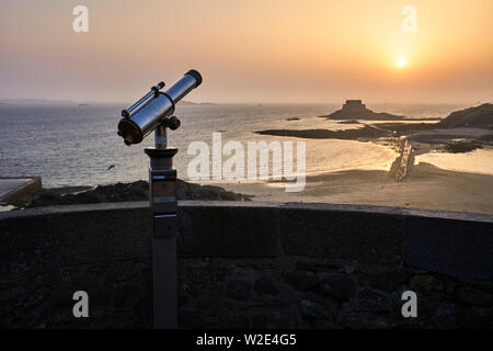 Un télescope de bord de mer donne sur une île et de coucher du soleil à St Malo, Bretagne, France Banque D'Images