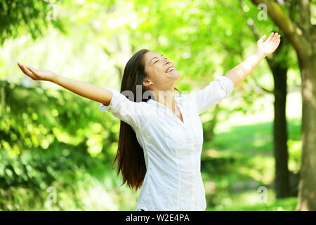 Jeune femme méditant à bras ouverts dans la verdure de source fraîche avec sa tête levés vers le ciel et ses yeux fermés se réjouir de la fraîcheur et de nouveaux débuts du printemps et de la nature Banque D'Images