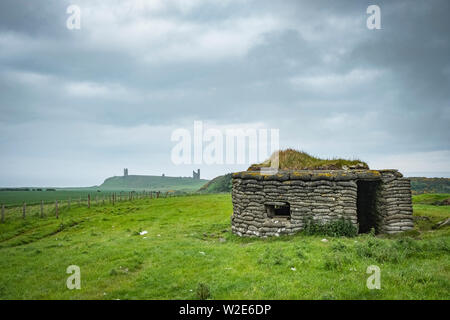 Guerre Mondiale deux Pilllbox avec Château de Dunstanburgh dans la distance, Northumberland, Angleterre Banque D'Images