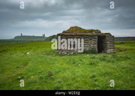 Guerre Mondiale deux Pilllbox avec Château de Dunstanburgh dans la distance, Northumberland, Angleterre Banque D'Images