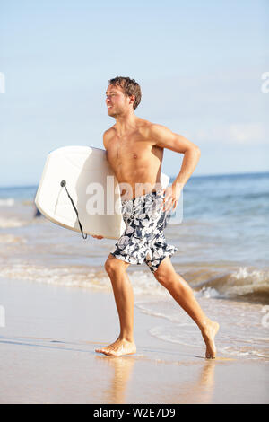 Beach Water sports homme avec corps en cours de surf en toute sécurité avec une assurance lors des vacances des vacances sur la plage tropicale aux beaux jours avec le ciel bleu et le soleil. Mâle beau modèle sport de remise en forme. Banque D'Images