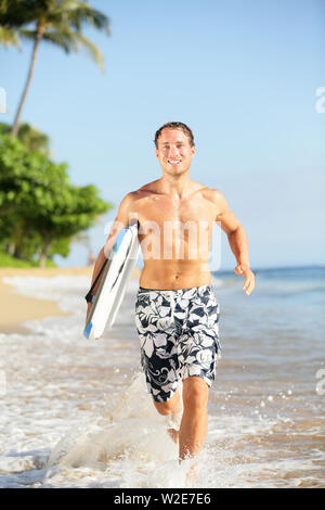 Plage de personnes - homme surfer avec surf bodyboard en marche dans l'eau on tropical beach. Modèle de remise en forme mâle ayant été locations de vacances fun sur la plage de Kaanapali, Maui, Hawaii, USA. Banque D'Images