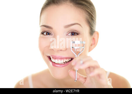 Femme maquillage des yeux à l'aide de cils de mascara. Beauté du visage soins cils girl smiling happy. Chinois asiatique multiraciale / Caucasian female model looking in mirror isolé sur fond blanc. Banque D'Images