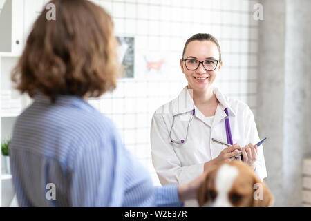 Le vétérinaire et le client avec le chien de discuter du traitement dans une clinique vétérinaire. Banque D'Images