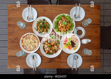 Thai appliqué le déjeuner ensemble comme les fruits de mer frit avec sauce, pizza, salade, saumon et crevettes frites sur la table en bois en vue de dessus et de l'angle il prêt à e Banque D'Images