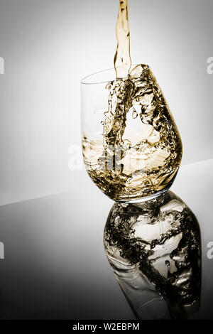 Verre de whisky isolé sur fond blanc avec la baisse de l'or liquide, couleur Banque D'Images