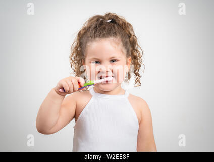 Cute blonde girl se brosser les dents isolées sur fond blanc Banque D'Images