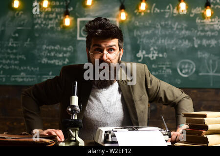 Businessman portent des lunettes sur le visage surpris. Homme à barbe à 24 à l'université. Homme barbu avec des livres et machine à écrire. La recherche scientifique avec Banque D'Images