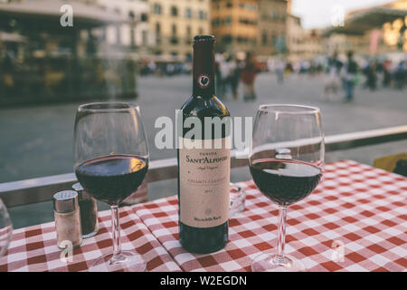 Florence, Italie - 24 juin 2018 : bouteille de vin rouge Chianti Classico Sant'Alfonso et des verres sur la table de restaurant sur fond de la Piazza d Banque D'Images