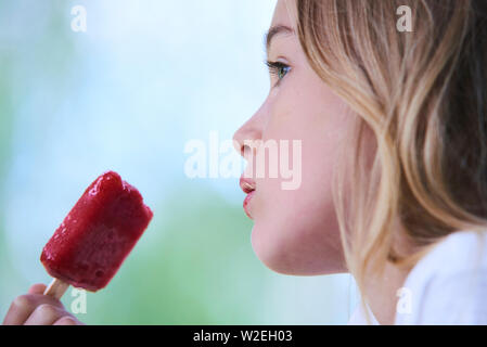 Belle petite fille mange de la glace aux fraises en été. Mise au point sélective Banque D'Images