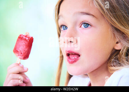 Belle petite fille mange de la glace aux fraises en été. Mise au point sélective Banque D'Images