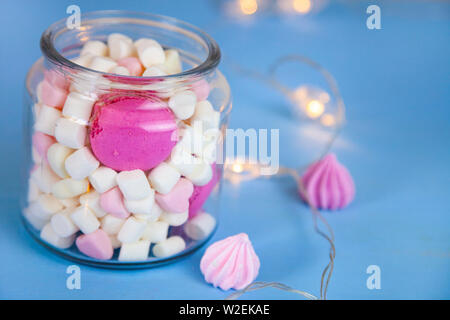 De la guimauve dans un bocal de verre et d'une guirlande de coeurs. Un délicieux dessert. Banque D'Images