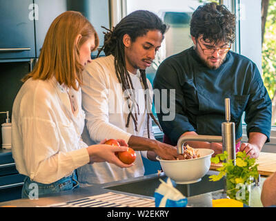 Couple interracial de mari et femme de race blanche de l'Afrique de préparer la nourriture avec un chef professionnel Banque D'Images