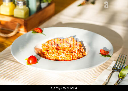 Risotto aux fruits de mer et la sauce tomate dans une assiette blanche sur la table dans le restaurant. Banque D'Images