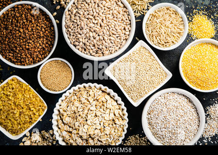Sélection de grains entiers dans des bols blancs : riz, avoine, sarrasin, boulgur, porridge, orge, quinoa, amarante Banque D'Images