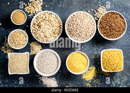 Sélection de grains entiers dans des bols blancs : riz, avoine, sarrasin, boulgur, porridge, orge, quinoa, amarante Banque D'Images