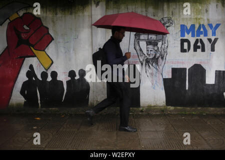 9 juillet 2019 - Dhaka, Bangladesh - un homme porte sur lui-même sous égide passe graffiti street en temps de pluie à Dhaka. Une dépression tropicale a continué d'apporter de fortes pluies dans le pays. (Crédit Image : © MD Mehedi Hasan/Zuma sur le fil) Banque D'Images