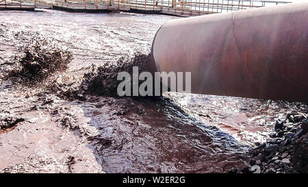 Les eaux usées industrielles sont déchargés par le tuyau dans l'eau. Banque D'Images