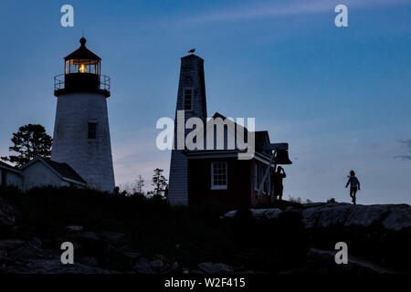 Les enfants qui se profile par le soleil couchant à l'historique Pemaquid Point Lighthouse à Bristol, dans le Maine. Le pittoresque phare construit sur la côte rocheuse de Pemaquid Point a été commandée en 1827 par le président John Quincy Adams. Banque D'Images
