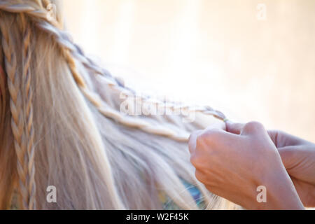 Femme Gros plan des mains gracieuses enchevêtrement de cheveux blond en petites tresses Banque D'Images