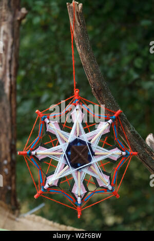 Closeup of a multi-couleur tissé main macrame dreamcatcher accroché à une branche dans le parc Banque D'Images