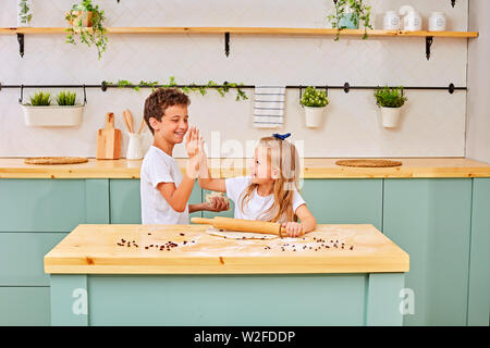 La famille aimante est heureux de préparer ensemble la boulangerie. frère et soeur sont la cuisson des cookies et d'avoir du plaisir dans la cuisine. Cuisine maison et peu d'aide Banque D'Images