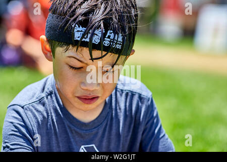 Prescott, Arizona, USA-Juillet 6, 2019 : jeune garçon se reposer après avoir été sur un toboggan gonflable à la guerre de l'eau, sur le Mile High Middle School fiel Banque D'Images