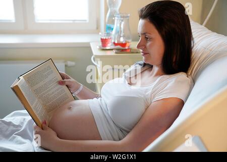 Risque de grossesse, femme enceinte, lit un livre au lit à l'hôpital, Karlovy Vary, République Tchèque Banque D'Images