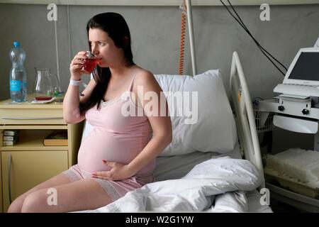 Pregnant woman sitting on lit dans chambre de malade, grossesse à haut risque, Karlovy Vary, République Tchèque Banque D'Images