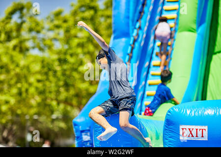 Prescott, Arizona, USA-Juillet 6, 2019 : jeune garçon de sortir un toboggan gonflable à la guerre de l'eau, sur le Mile High Middle School field au centre-ville de Pr Banque D'Images