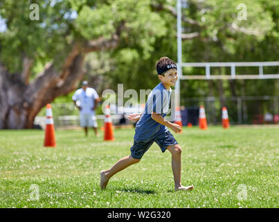 Prescott, Arizona, USA-Juillet 6, 2019 : Jeune garçon courir pieds nus sur une pelouse à la Mile High Middle School field au centre-ville de Prescott Banque D'Images