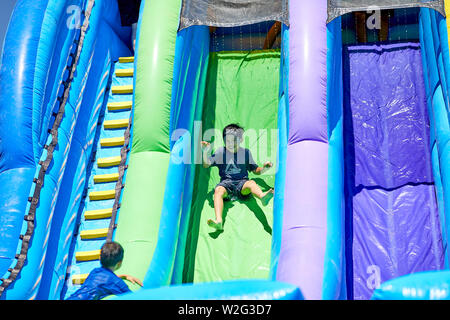 Prescott, Arizona, USA-Juillet 6, 2019 : jeune garçon en glissant sur un toboggan gonflable à la guerre de l'eau, sur le Mile High Middle School en champ downto Banque D'Images