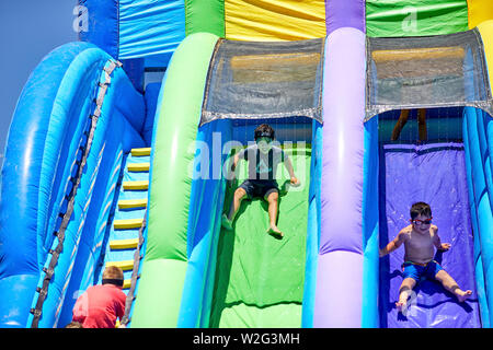 Prescott, Arizona, USA-Juillet 6, 2019 : jeune garçon en glissant sur un toboggan gonflable à la guerre de l'eau, sur le Mile High Middle School en champ downto Banque D'Images