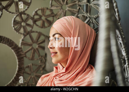 Pretty smiling pensive young woman with freckles portant hijab rose clair Banque D'Images
