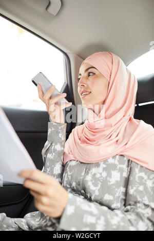 Belle Dame d'affaires en hijab de l'enregistrement du son message à un collègue lors de l'équitation au travail ou d'une réunion Banque D'Images