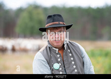 Doberlug Kirchhain, Allemagne. 08 juillet, 2019. René Berger Jeronimus se place en avant d'un troupeau de chèvres et moutons sur le Weißhaus site du patrimoine naturel. Credit : Soeren Stache/dpa/Alamy Live News Banque D'Images