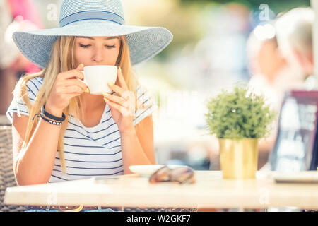 Belle fille de boire du café dans un café terrasse. Portrait de l'été jeune femme. Banque D'Images