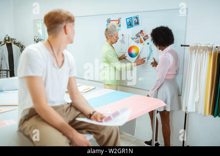 Deux designers. Deux créateurs de mode femme debout devant le tableau blanc en discutant de la palette de couleurs Banque D'Images