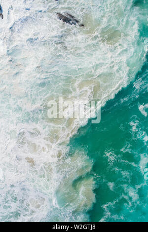 Vue aérienne d'une vagues se briser et le matériel roulant dans l'océan. Photos d'une tempête à la mer, l'océan et l'eau bleue avec des motifs de sable Banque D'Images