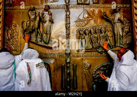 Pèlerins éthiopiens de toucher la porte principale de la basilique catholique de l'Annonciation à Nazareth, Tibériade, Israël. Banque D'Images