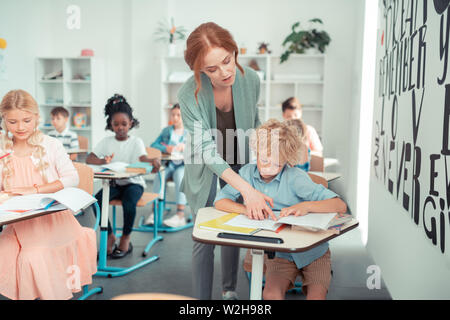 Aider l'enseignant un écolier de lire la tâche. Banque D'Images