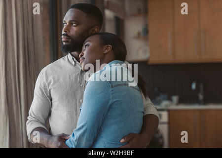 African American couple hugging et regardant par la fenêtre Banque D'Images