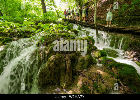 Les randonneurs se promener le long de la passerelle en bois de l'eau des cascades de passage se précipiter la roche au parc national des Lacs de Plitvice, Croatie Banque D'Images